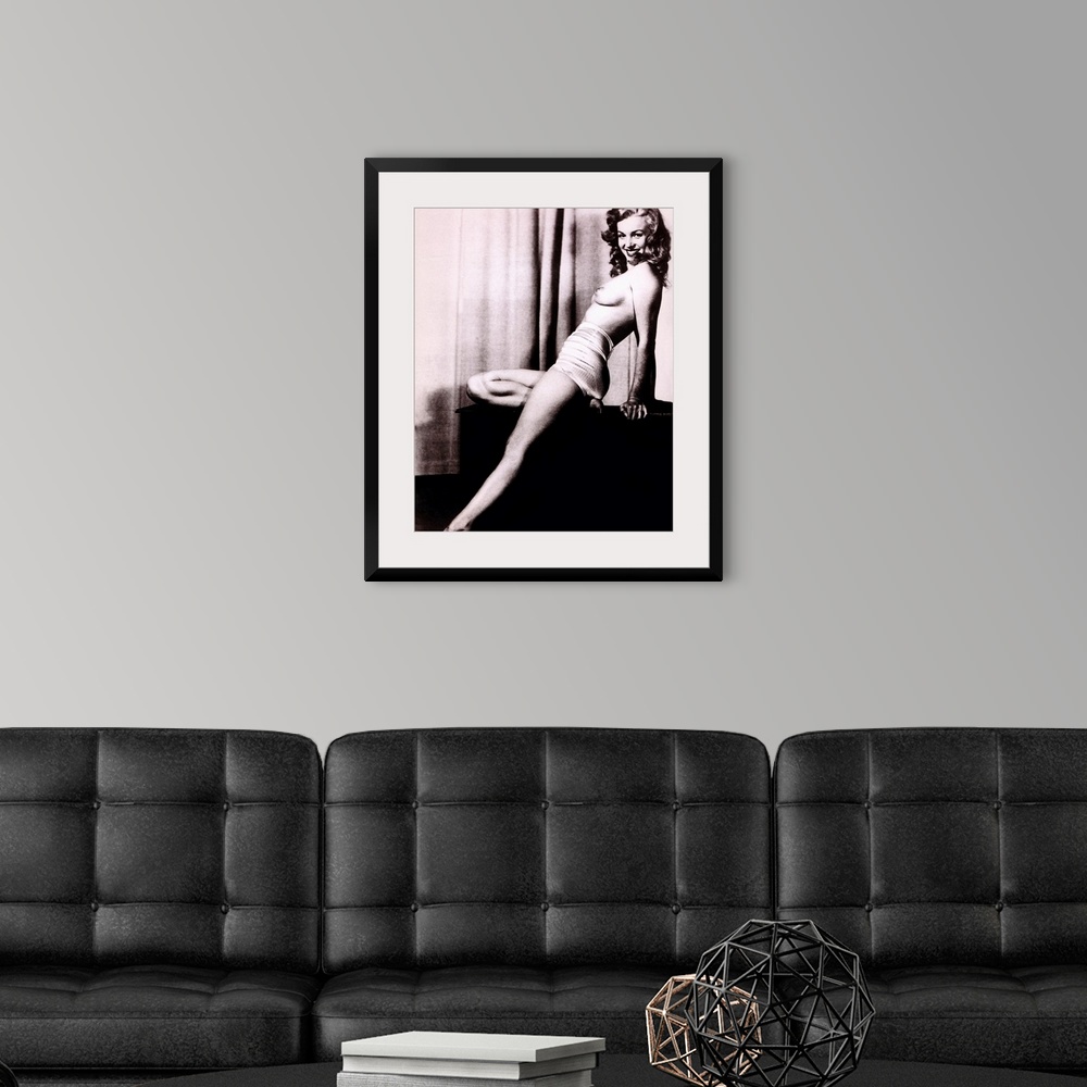 A modern room featuring Boudoir photo of Marilyn Monroe topless and leaning back on a stand in front of a curtain, smilin...