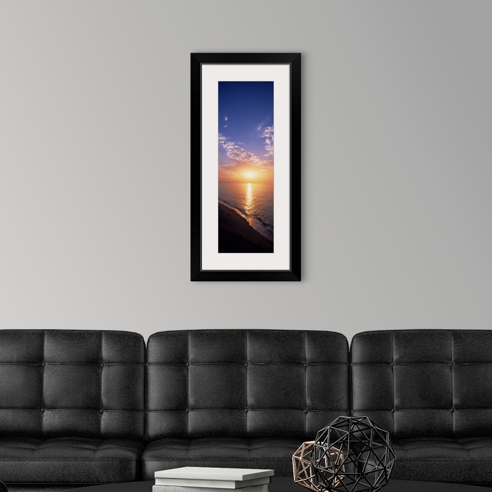 A modern room featuring Vertical panorama of the sun rising on the horizon of the Atlantic ocean, as seen from a sandy be...