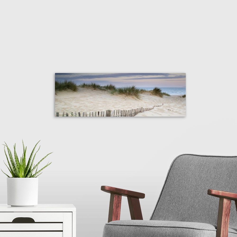 A modern room featuring Panorama landscape of sand dunes on beach at sunrise.