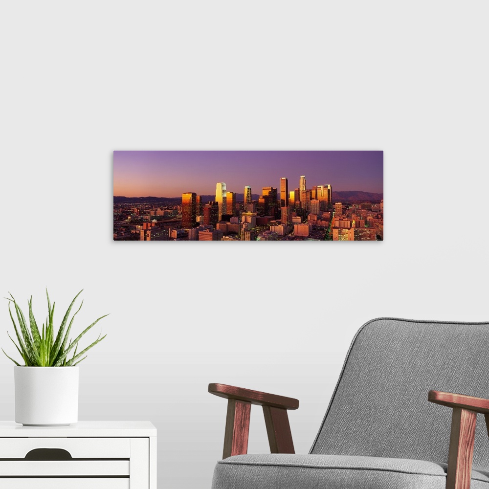 A modern room featuring Panoramic photograph of west coast city skyline at dusk.  The buildings and skyscrapers are lit u...