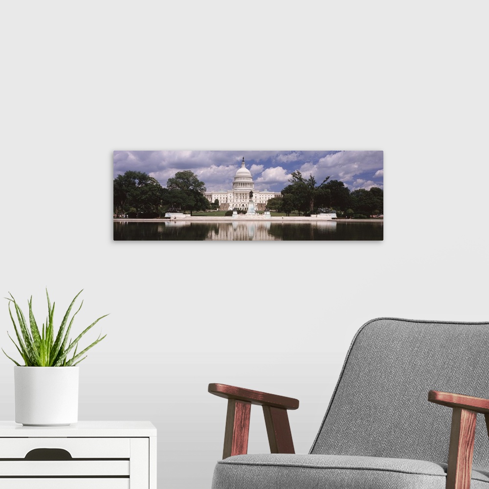 A modern room featuring Panoramic photograph of municipal building at water's edge surrounded by trees under a cloudy sky.