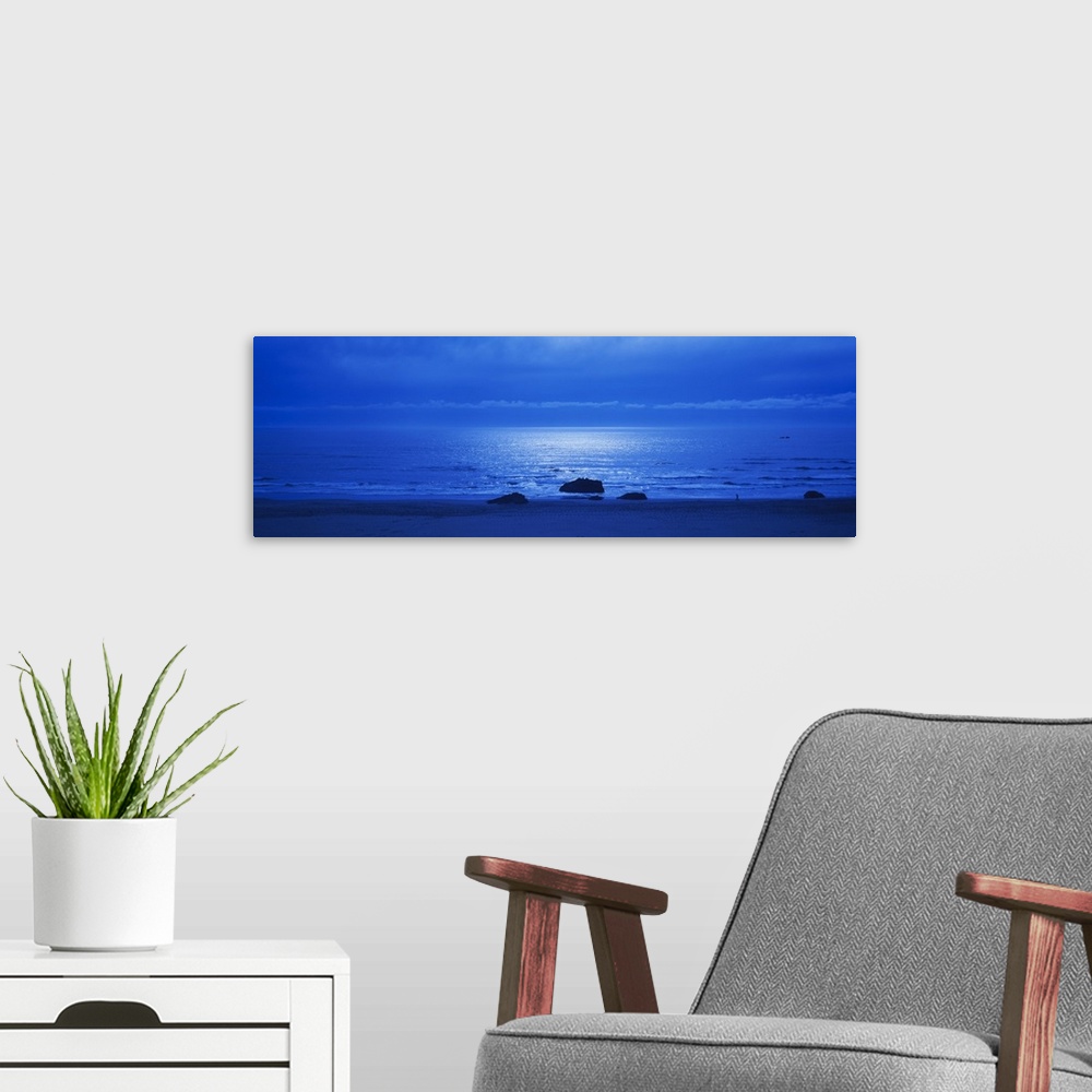 A modern room featuring Panoramic photograph of a monotone seascape with the moonlight reflecting off the waves, three so...