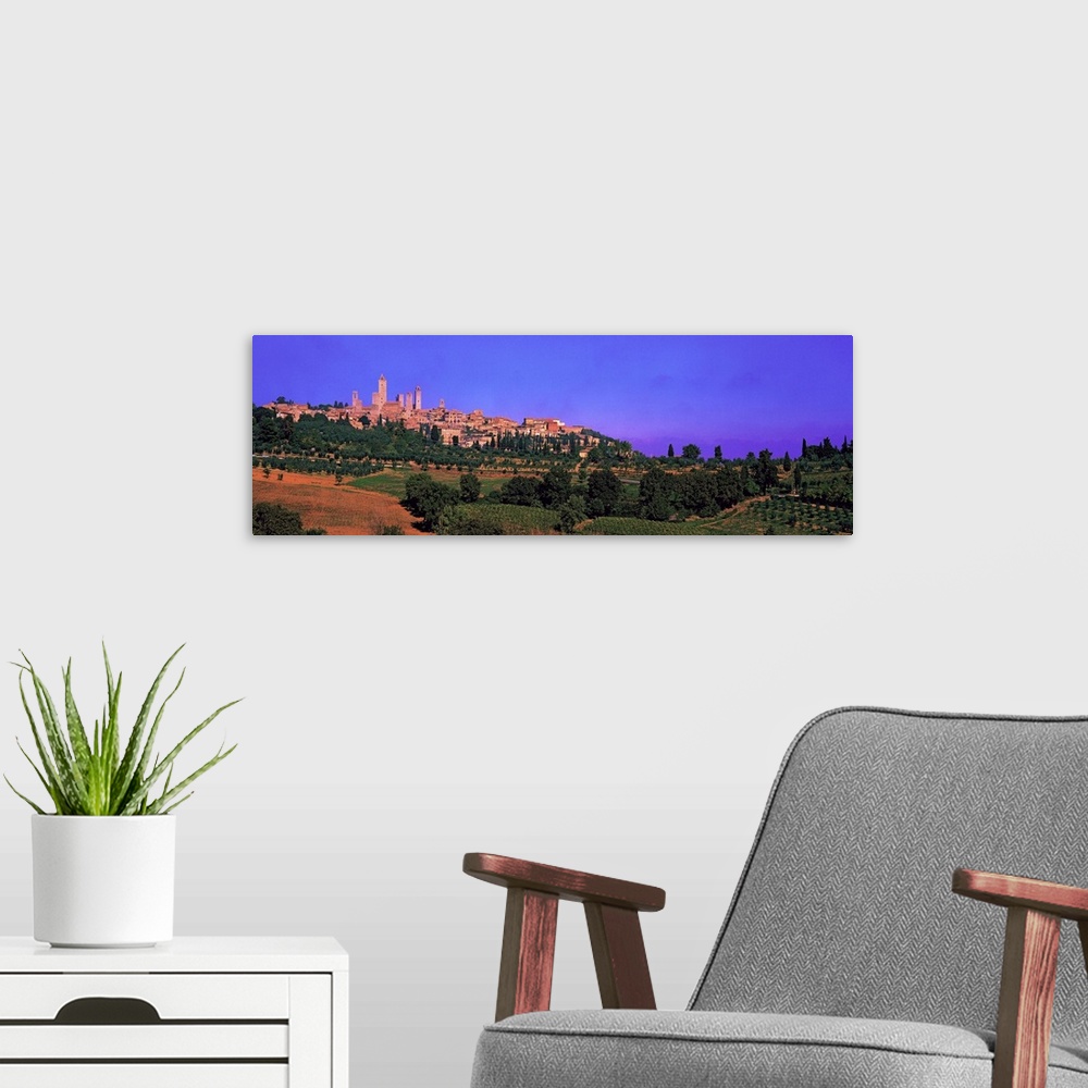 A modern room featuring Wide angle photograph of San Gimignano in the distance, against a vibrant sky. Green landscape an...