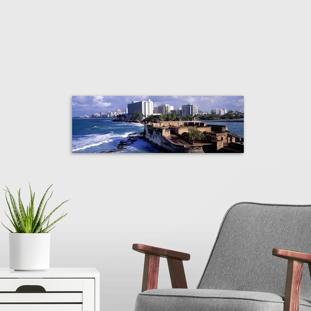 A modern room featuring Panoramic photograph of San Jeronimo Fort on the waters of San Juan, the city skyline in the back...