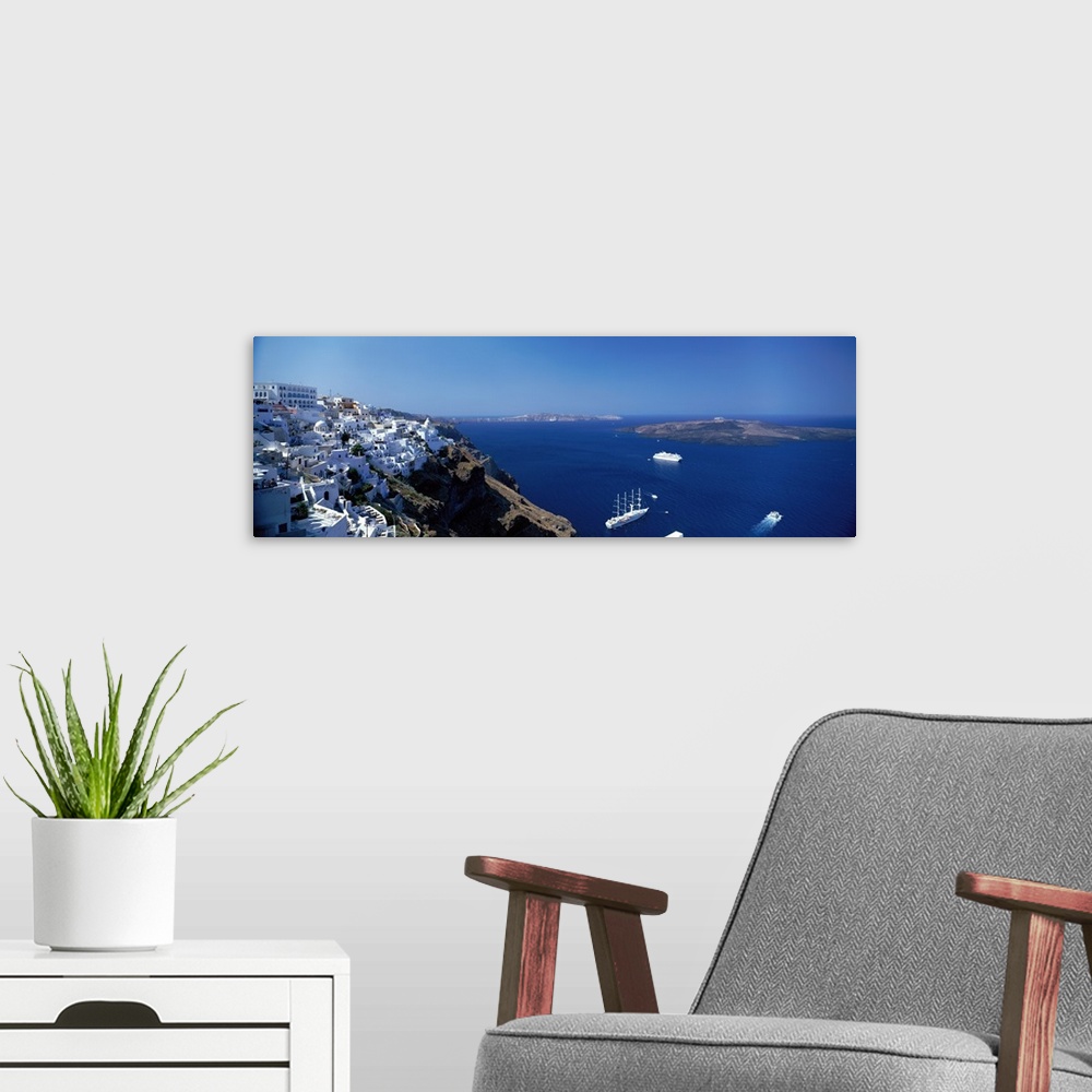 A modern room featuring Scenic photo of white houses sitting on the mountain Cliffside in Santorini, Greece with blue oce...