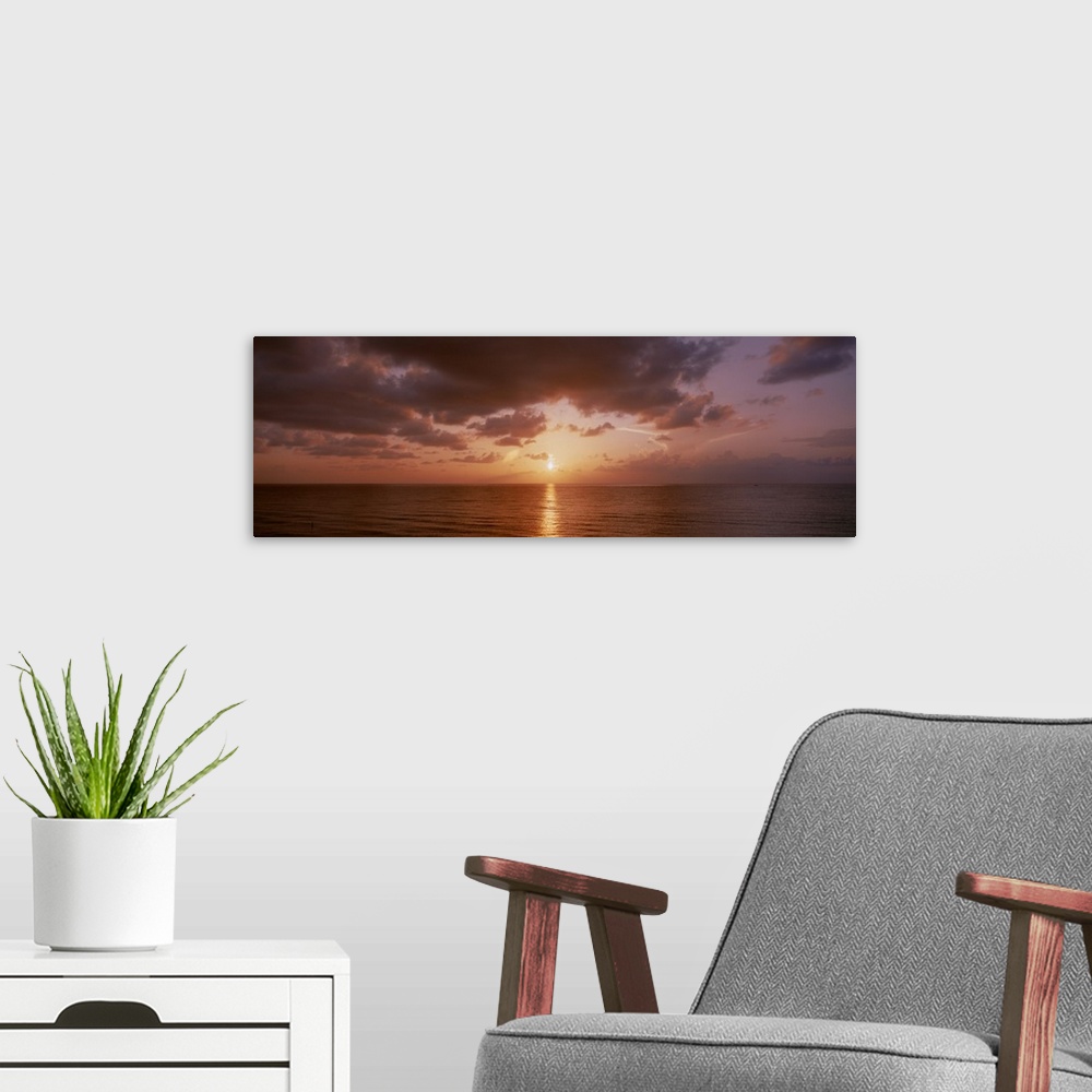 A modern room featuring Panoramic photograph of ocean at dawn under a cloudy sky.