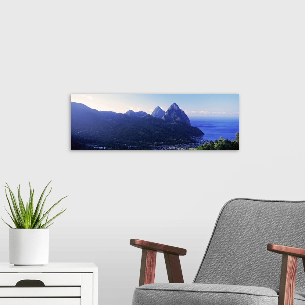 A modern room featuring The town of Soufriere is pictured in panoramic view with the water just to the right and the sun ...