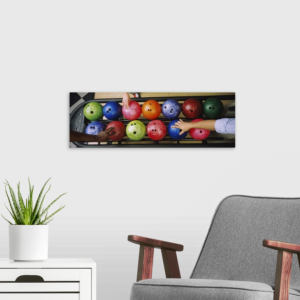 A modern room featuring Three peoples hands choosing bowling balls