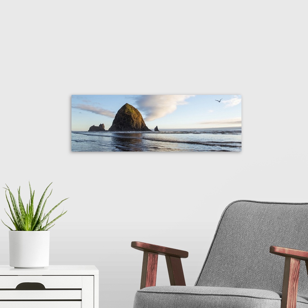 A modern room featuring Panoramic photograph of Haystack Rock with a bird flying in the sky at Cannon Beach.