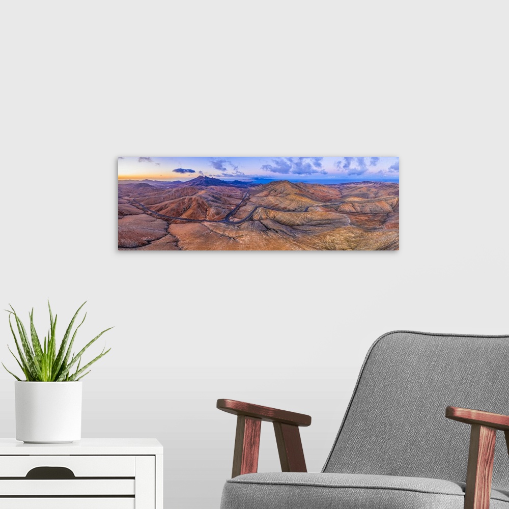 A modern room featuring Mountain road crossing the volcanic landscape near Sicasumbre astronomical viewpoint, Fuerteventu...