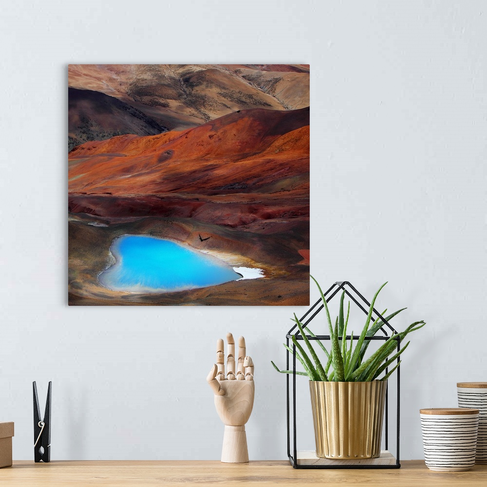 A bohemian room featuring A bright blue heart-shaped lake contrasts with the orange hills of the surrounding desert.