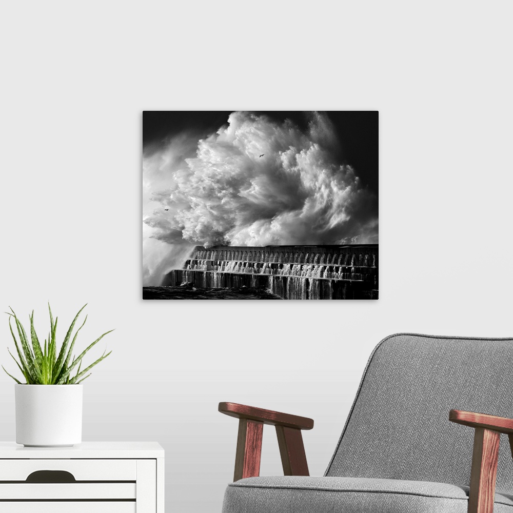 A modern room featuring A black and white photograph of a massive wave crashing over a pier.
