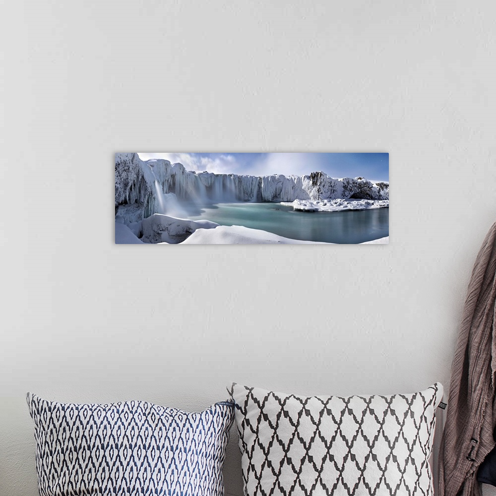 A bohemian room featuring Icy snow covered landscape with waterfalls streaming down from cliffs surrounding a river.