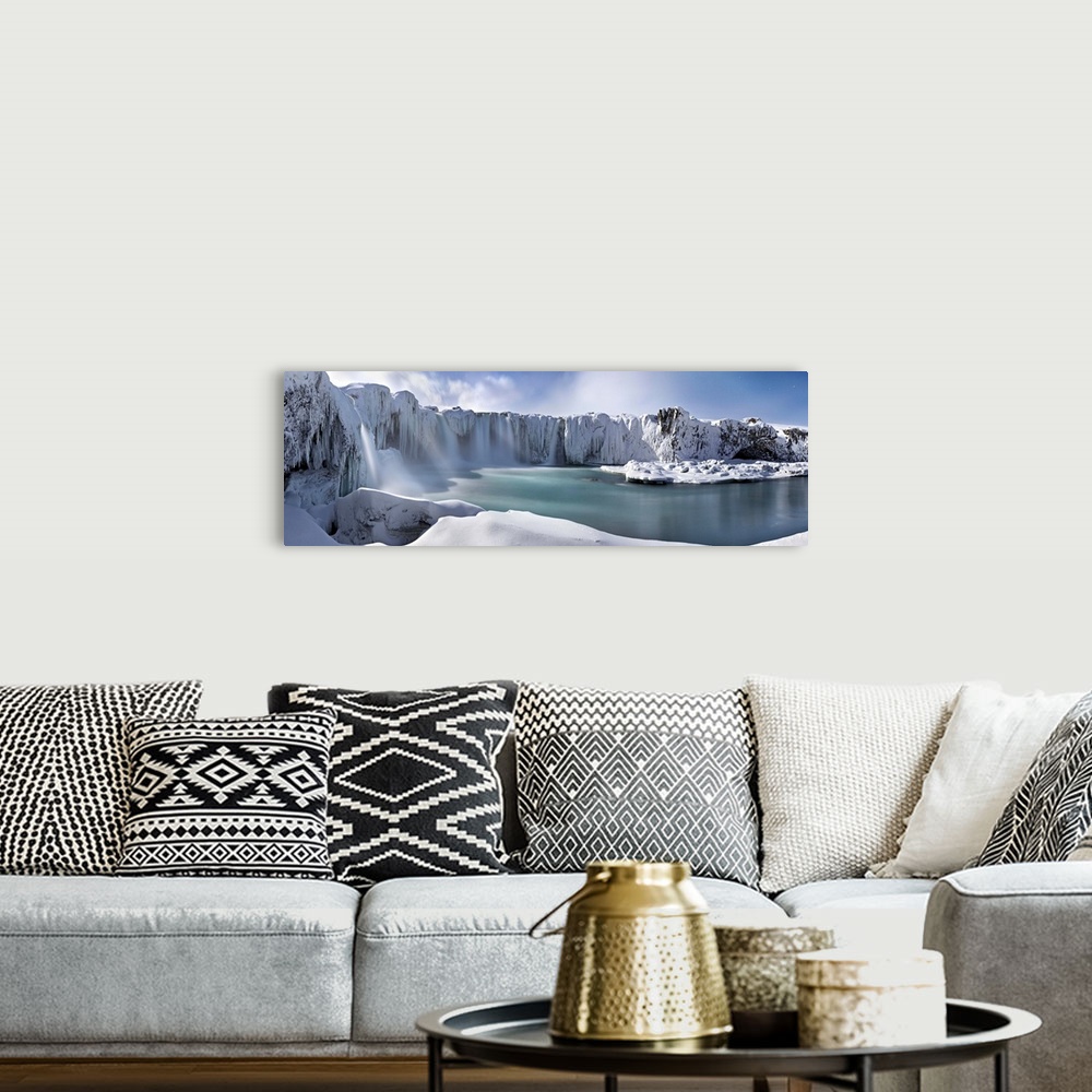 A bohemian room featuring Icy snow covered landscape with waterfalls streaming down from cliffs surrounding a river.