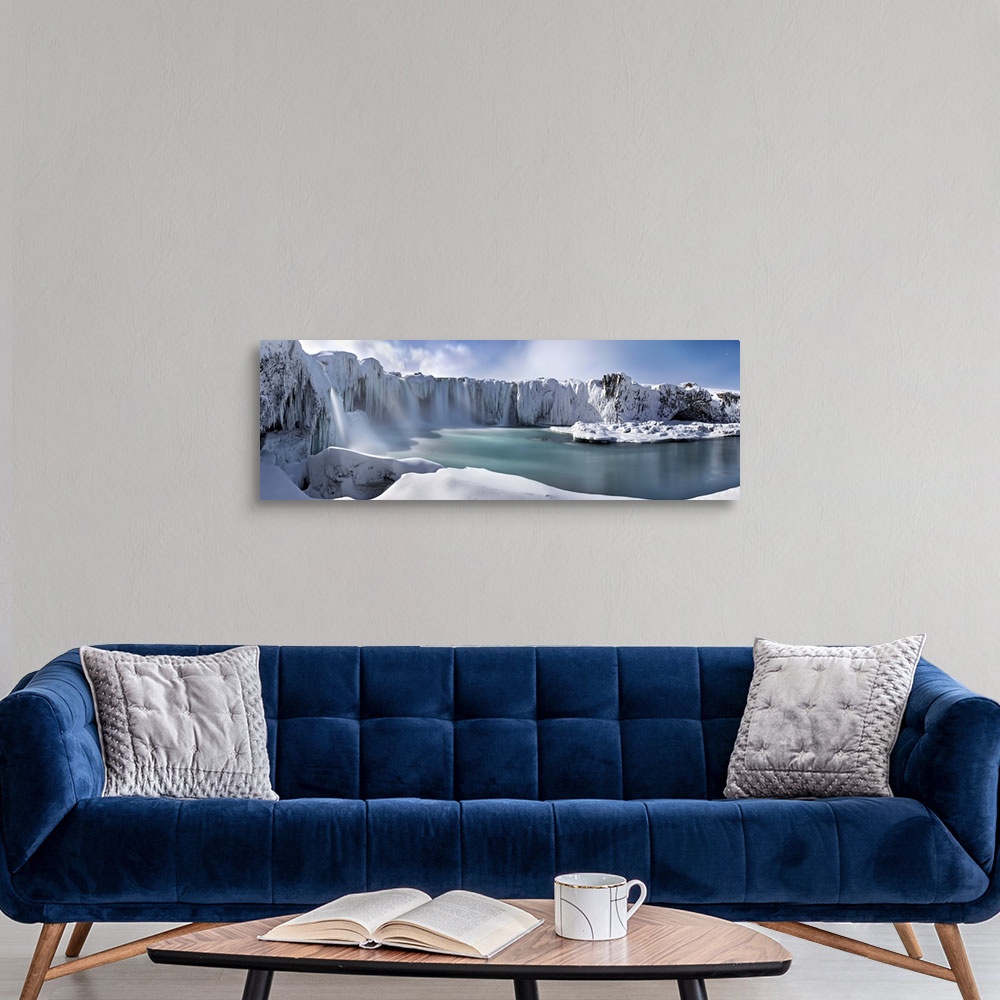 A modern room featuring Icy snow covered landscape with waterfalls streaming down from cliffs surrounding a river.