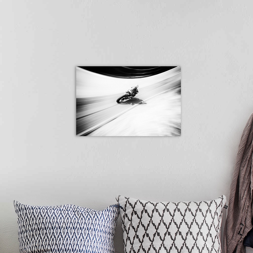 A bohemian room featuring A figure on a motorcycle traveling fast on a curved road.