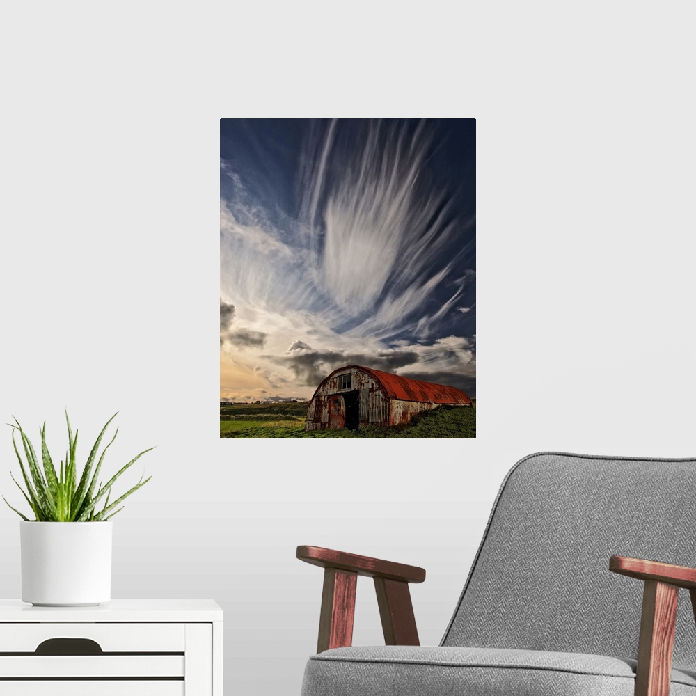 A modern room featuring A rusty dilapidated building in a green field under a sky filled with dramatic clouds, Iceland.
