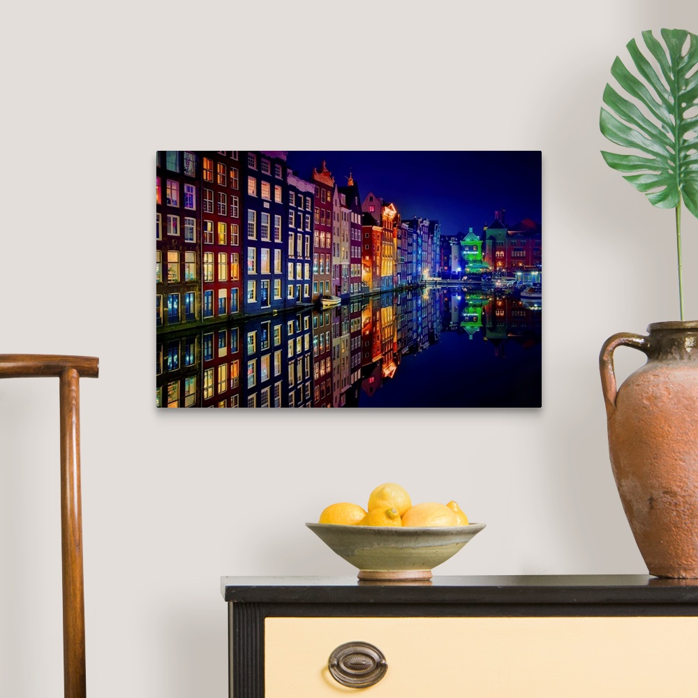 A traditional room featuring A glowing row of buildings in Amsterdam reflecting in the canal below.