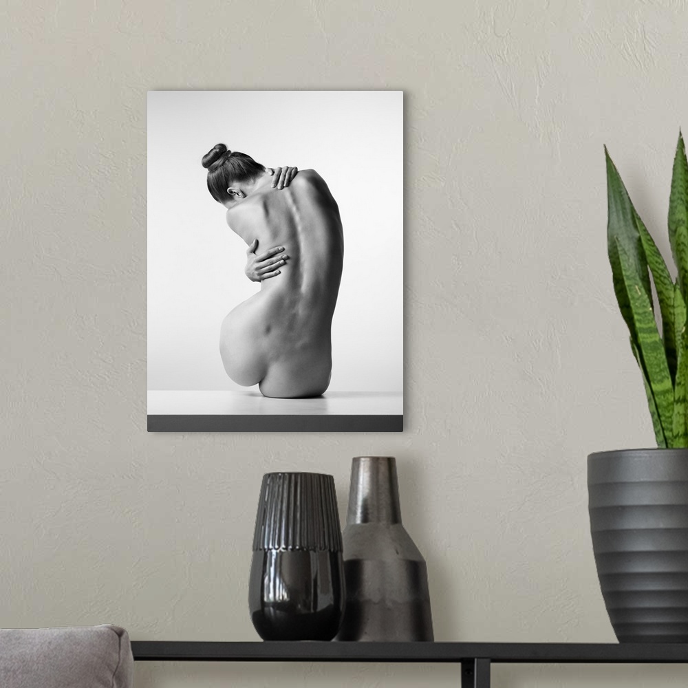 A modern room featuring Black and white fine art photograph of a nude woman from behind creating movement with her body.