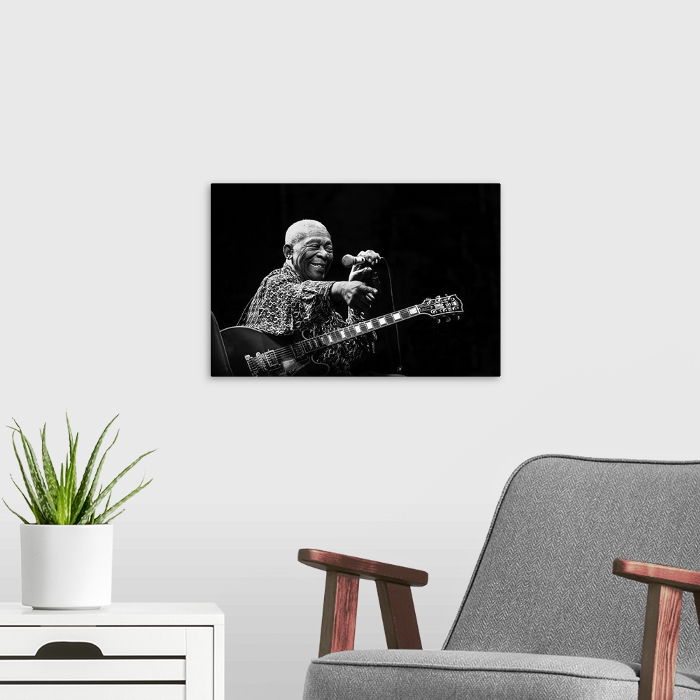 A modern room featuring Portrait of a blues musician on stage pointing to a fan in the crowd.
