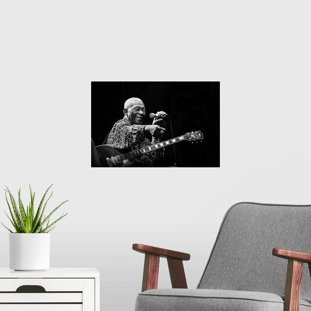 A modern room featuring Portrait of a blues musician on stage pointing to a fan in the crowd.