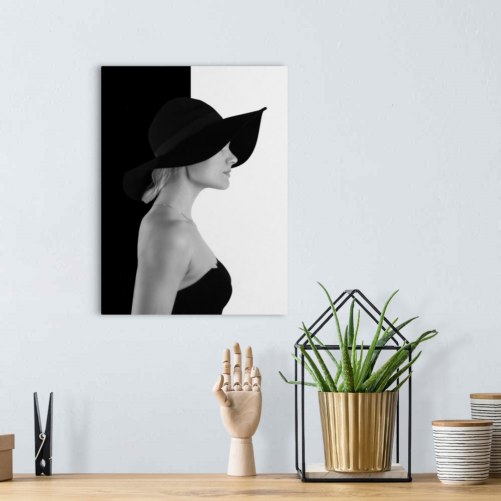 A bohemian room featuring Portrait of a woman with a black hat, against a half black, half white wall.
