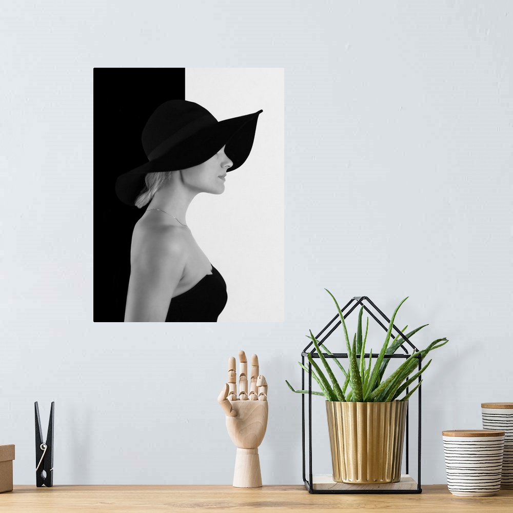 A bohemian room featuring Portrait of a woman with a black hat, against a half black, half white wall.