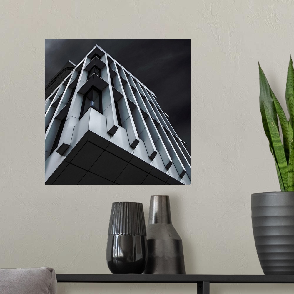 A modern room featuring Square abstract black and white photograph with a blue tint looking up at a modern building.
