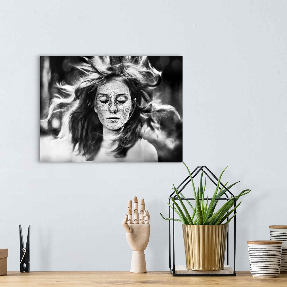 A bohemian room featuring A freckled young woman with closed eyes and her hair blowing in the wind.