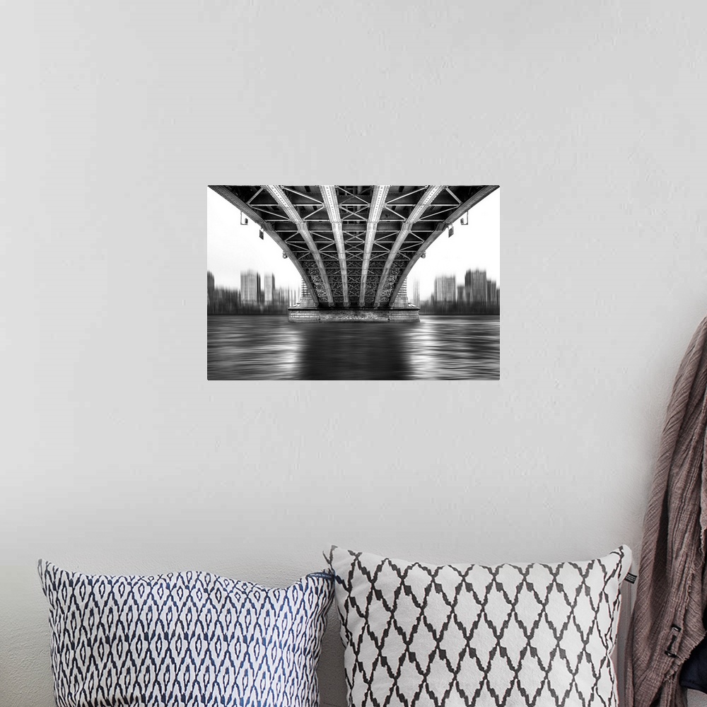 A bohemian room featuring A black and white photograph from under a large bridge looking across the river it spans to see a...