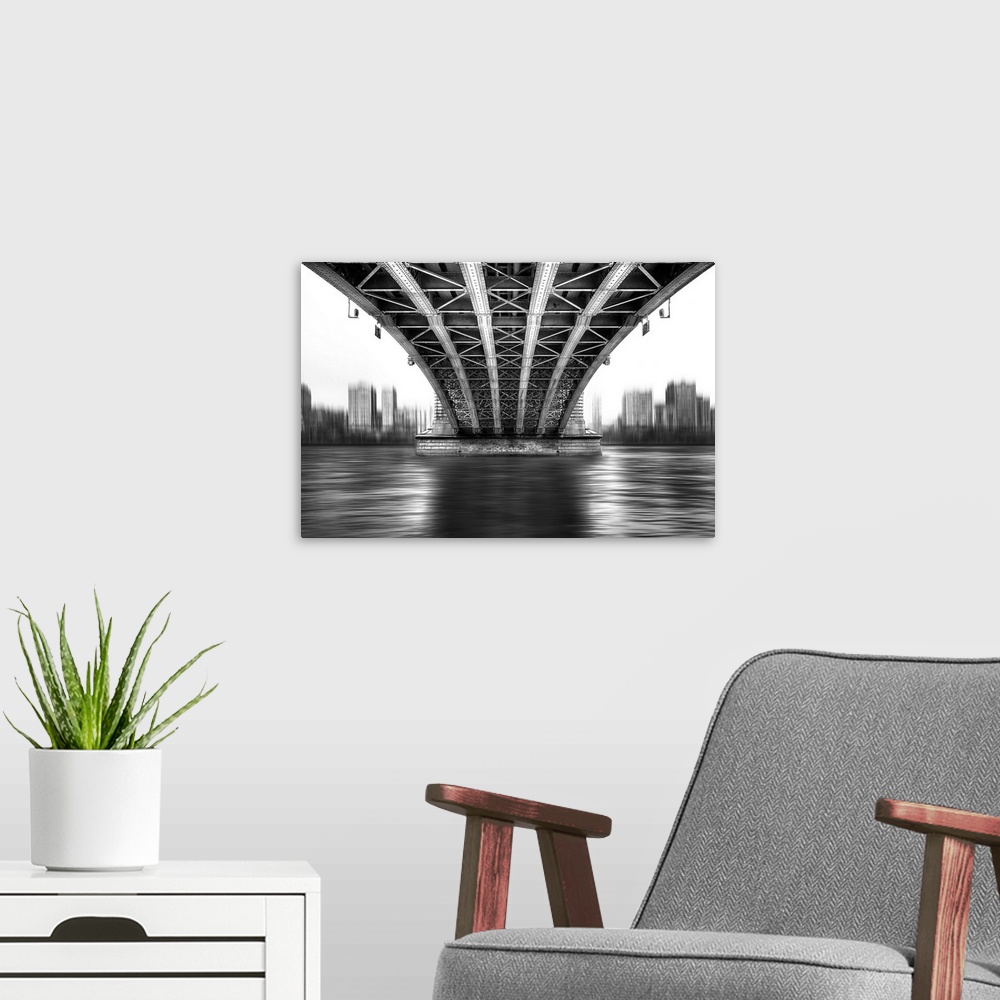 A modern room featuring A black and white photograph from under a large bridge looking across the river it spans to see a...