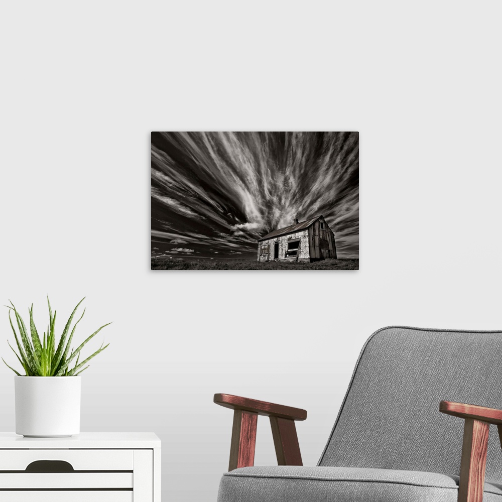 A modern room featuring High contrast photo of a cabin in Iceland with clouds streaking overhead.