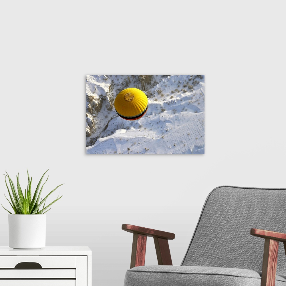 A modern room featuring A yellow hot air balloon floats above the snow covered landscape of Cappadocia, Turkey.