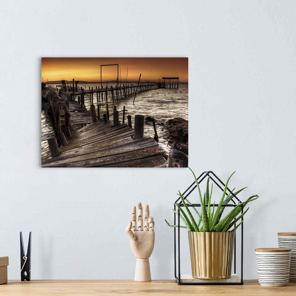 A bohemian room featuring A decaying wooden pier in Carrasqueira, Spain, at sunset.