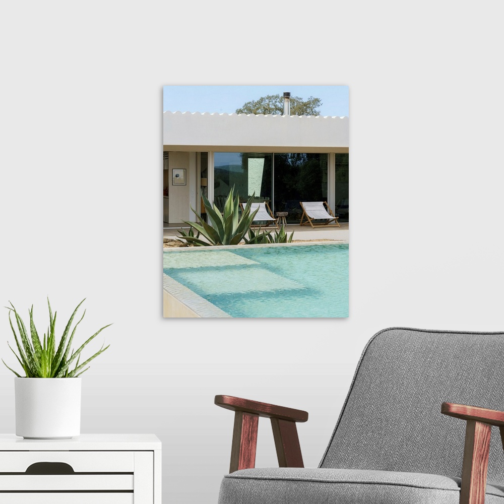 A modern room featuring A cool-toned photograph of an outdoor mediterranean swimming pool and villa