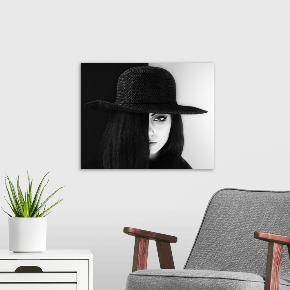A modern room featuring Portrait of a woman with face half obscured, wearing a large hat.