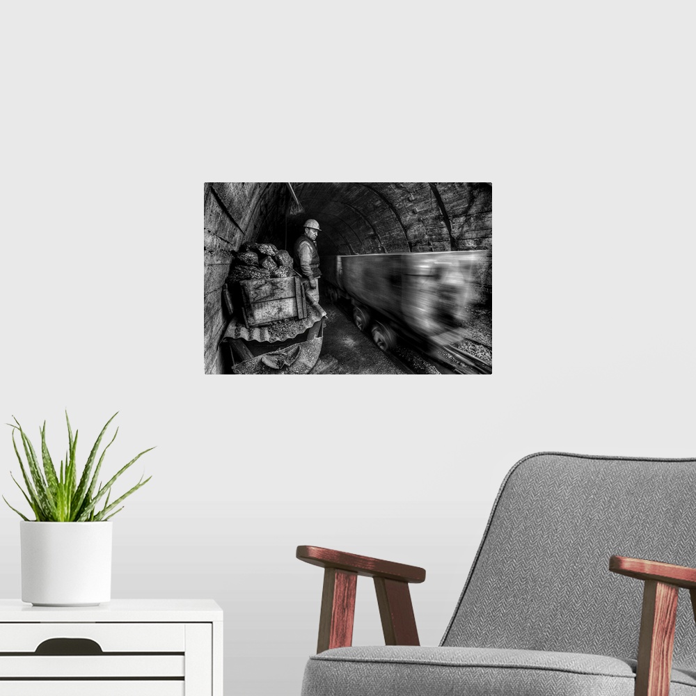 A modern room featuring coal miners watching a mining cart whiz by in a cave.