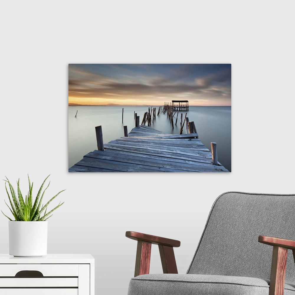 A modern room featuring A broken wooden pier off the coast of Carrasqueira, Portugal, at sunset.