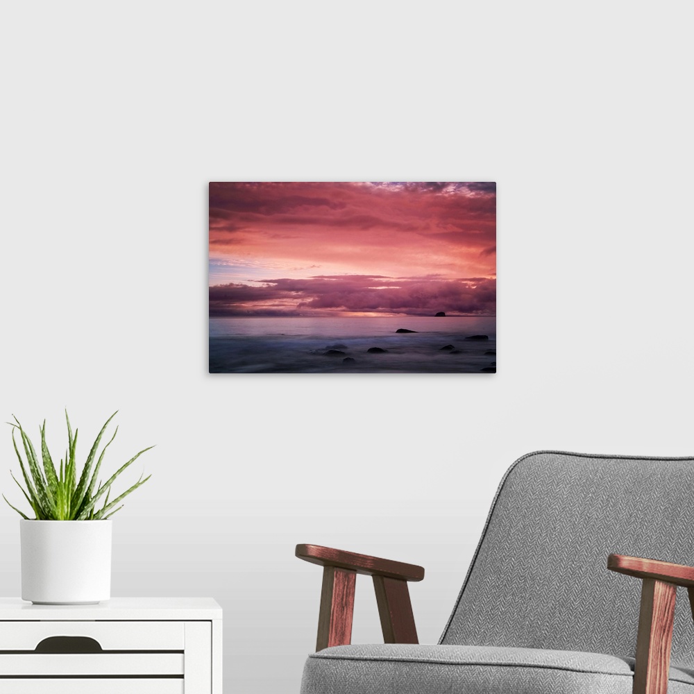 A modern room featuring A warm sunset over seascape in New Zealand.