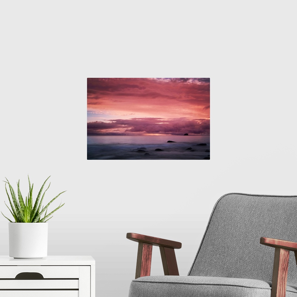 A modern room featuring A warm sunset over seascape in New Zealand.