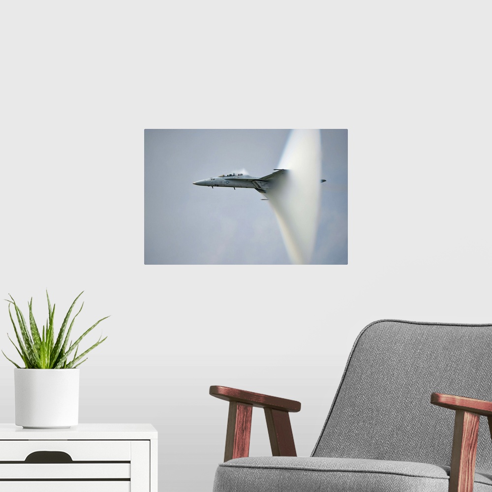 A modern room featuring A F/A-18 Super Hornet forming a cone of air as it breaks the sound barrier.