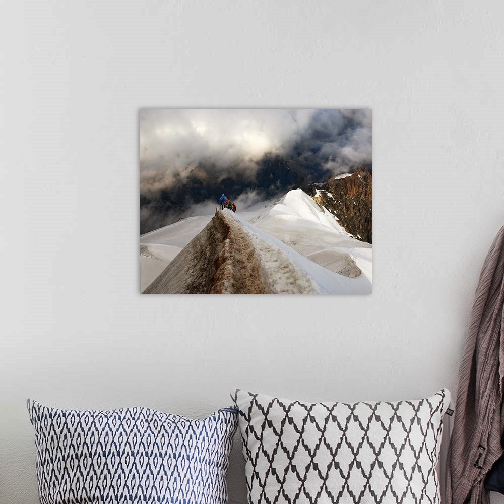 A bohemian room featuring Mountain climbers trekking across a snowy peak on their way to mountains obscured by clouds.