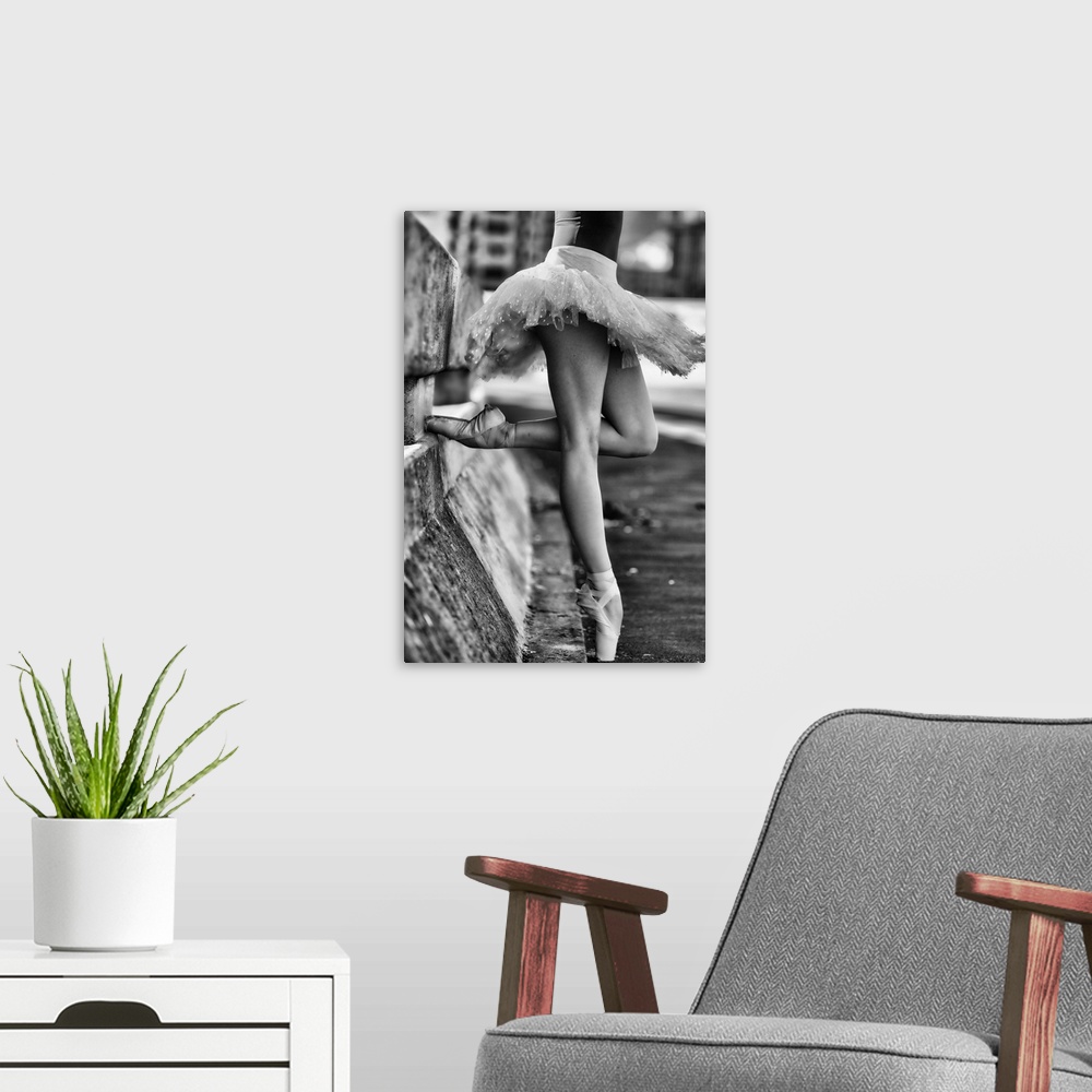 A modern room featuring A black and white photograph of a ballerina in a dancers pose leaning against a road divider outd...