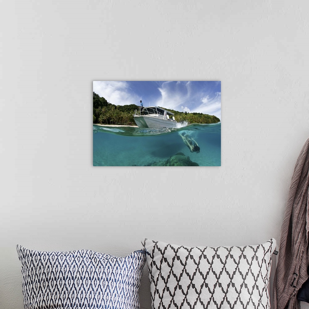 A bohemian room featuring A snorkeler dives underwater near a boat in a tropical Fiji bay.