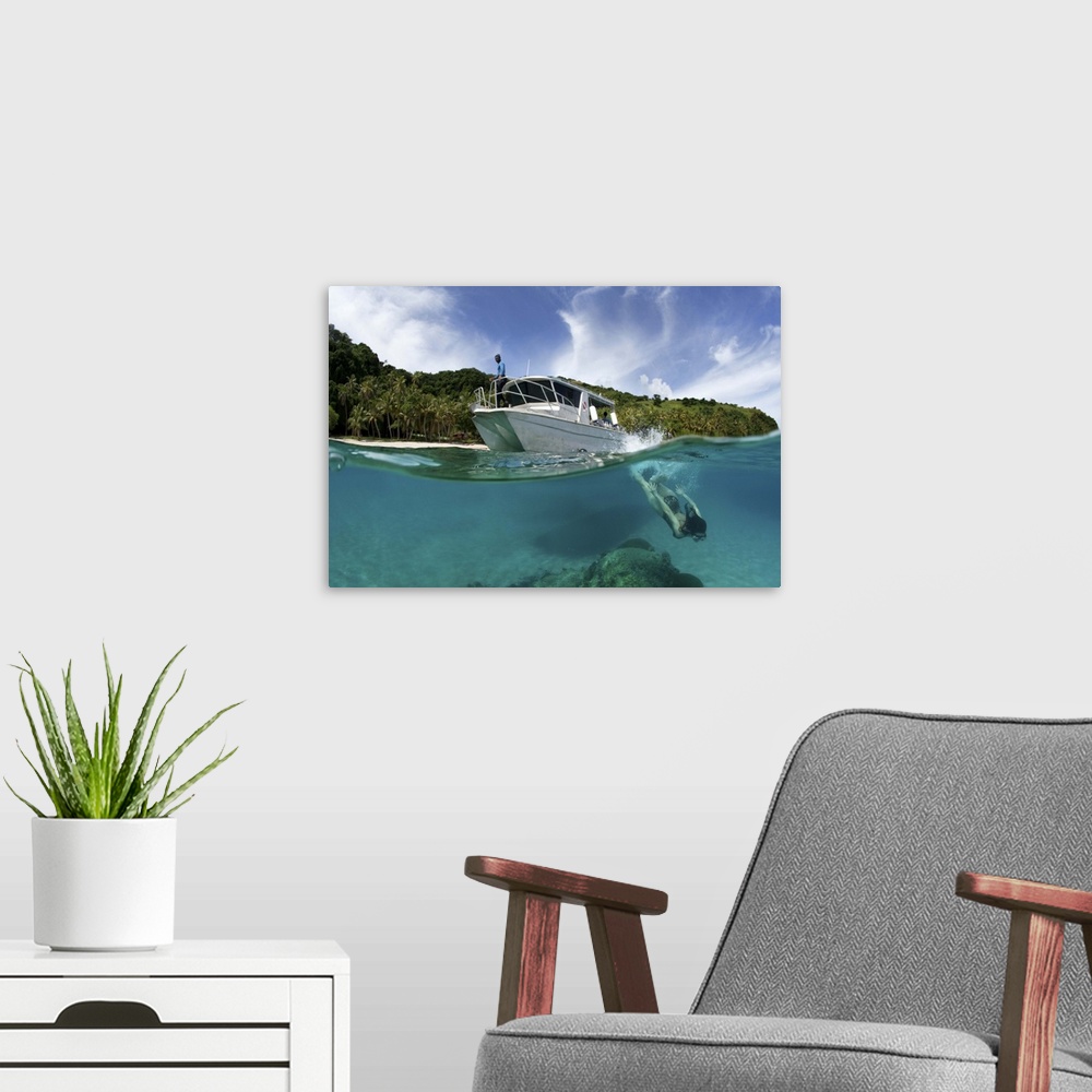 A modern room featuring A snorkeler dives underwater near a boat in a tropical Fiji bay.
