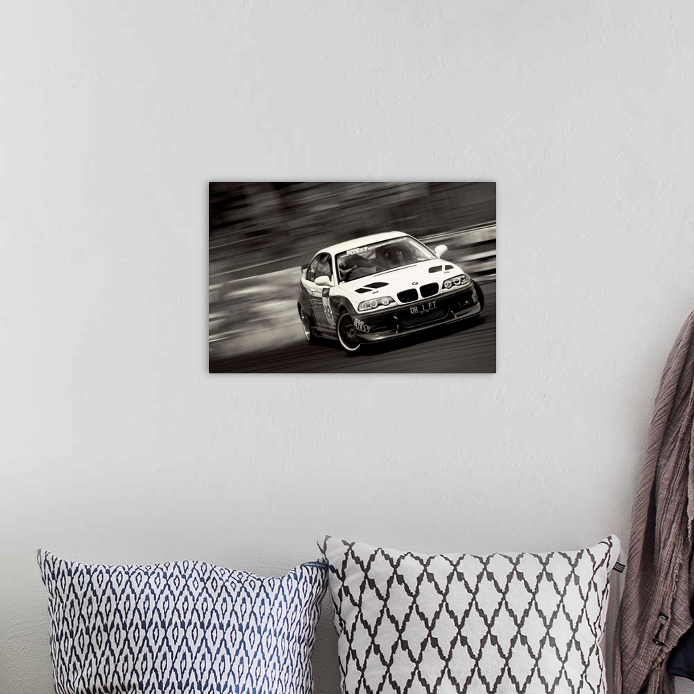 A bohemian room featuring A black and white photograph of a sports car drifting against a blurred background.