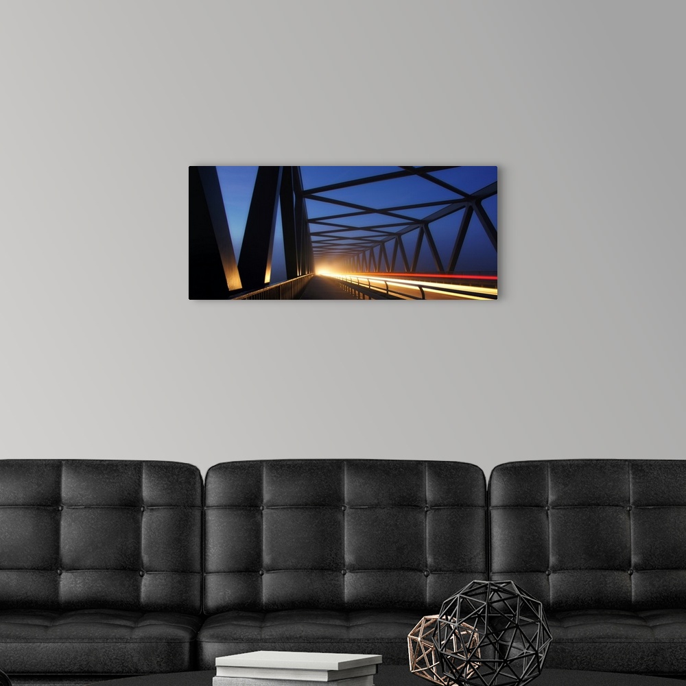 A modern room featuring Light trails on a bridge with cross beams forming simple shapes in the morning.