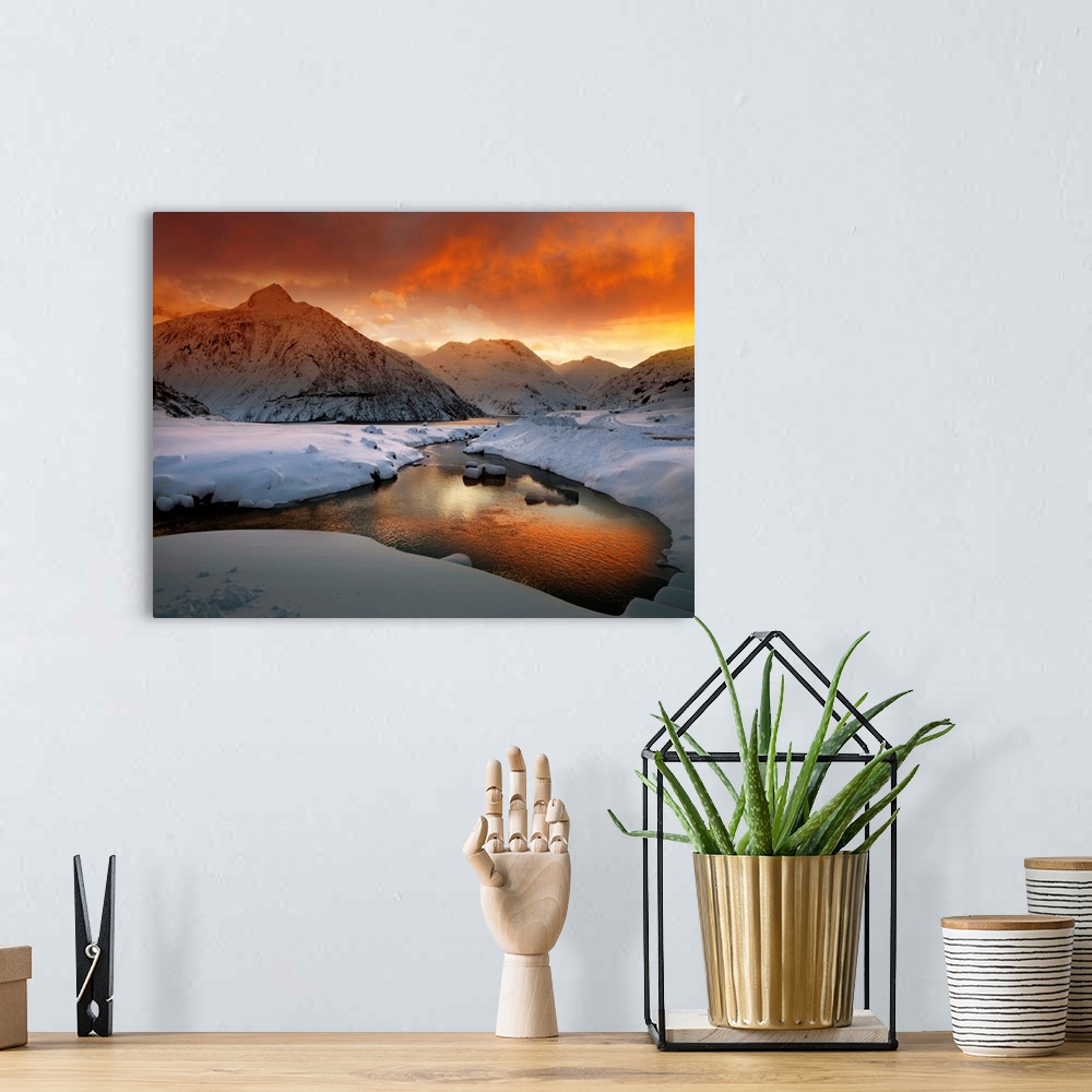 A bohemian room featuring A river in a snowscape reflecting the orange color of the sunrise, in the Austrian Alps.