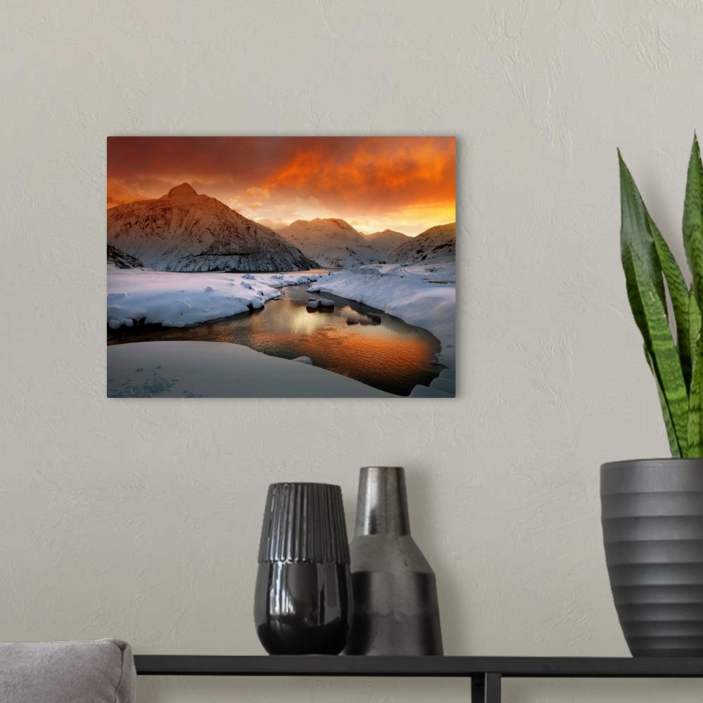 A modern room featuring A river in a snowscape reflecting the orange color of the sunrise, in the Austrian Alps.