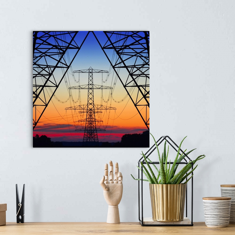 A bohemian room featuring Looking the center of electrical pylons silhouetted in the setting sun behind them.